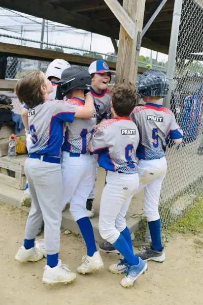 A group of youth baseball players hugging after a victory.