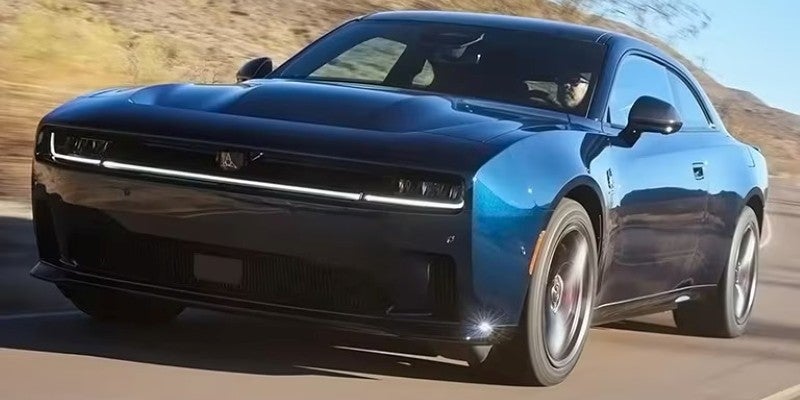 Dark blue electric Dodge Charger driving on an open road