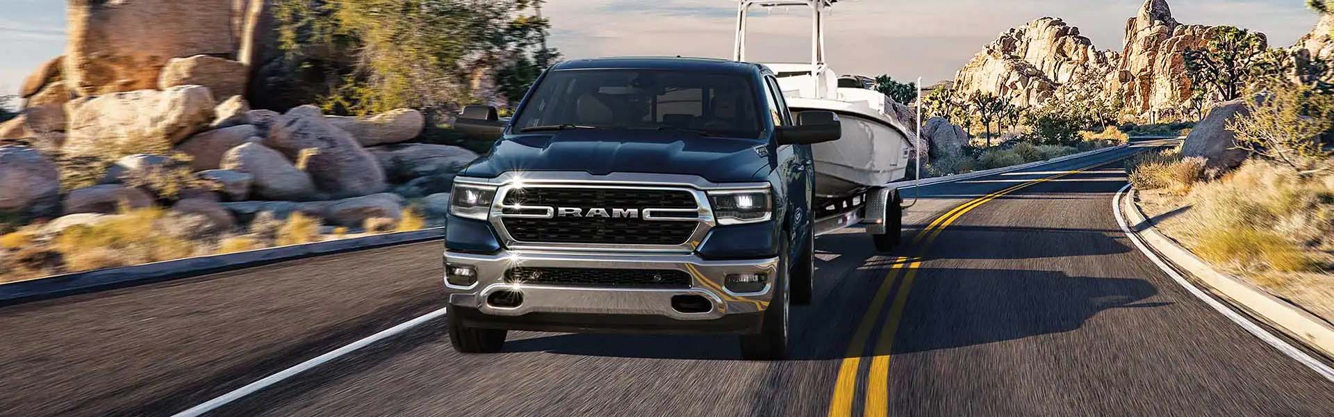 2023 Ram 1500 towing a boat on a desert highway with blurred motion.