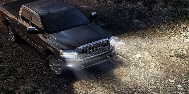 Overhead view of a black Ram truck on a rocky path, its headlights illuminating the ground ahead.